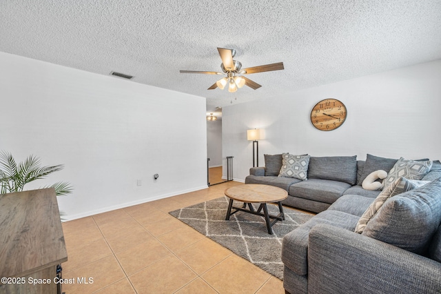 tiled living room with a textured ceiling, visible vents, a ceiling fan, and baseboards