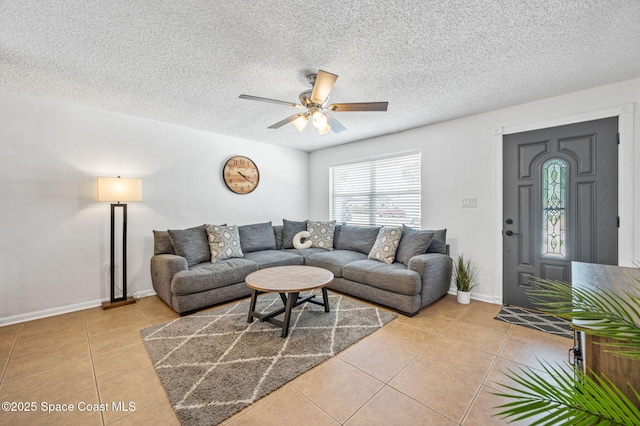 living area with ceiling fan, baseboards, a textured ceiling, and light tile patterned floors