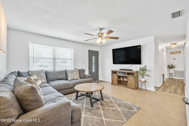 living room featuring ceiling fan, visible vents, and light tile patterned floors