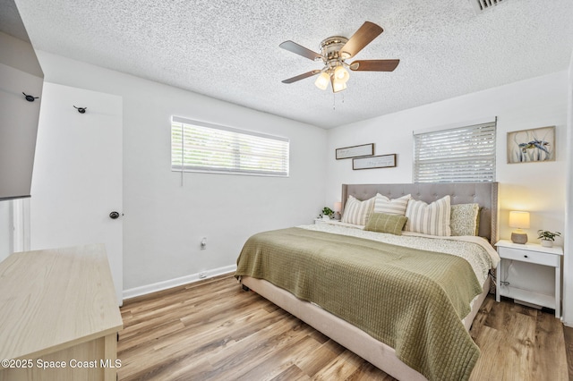 bedroom with baseboards, a ceiling fan, wood finished floors, and a textured ceiling