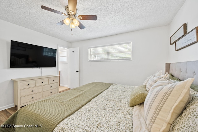 bedroom featuring a ceiling fan, wood finished floors, and a textured ceiling