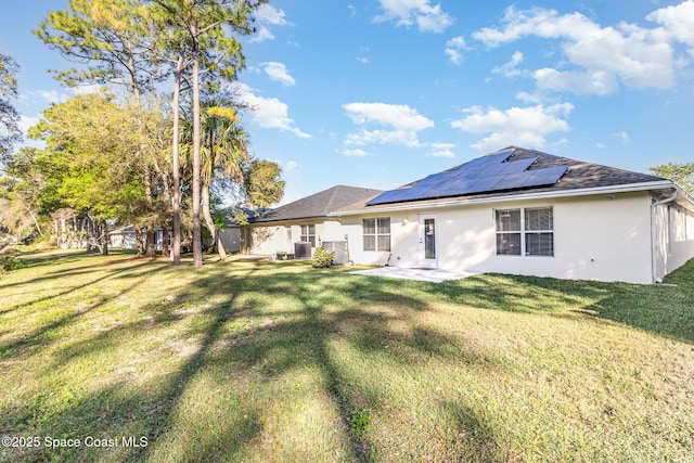 1461 Morgan Ct, Melbourne, FL 32934 - back of house featuring stucco siding, roof mounted solar panels, central AC unit, and a lawn