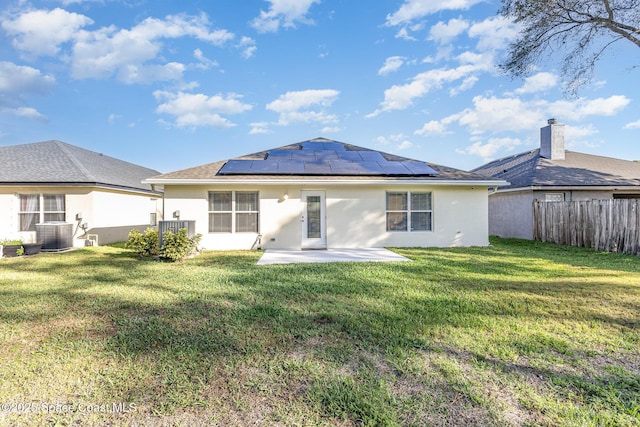 1461 Morgan Ct, Melbourne, FL 32934 - rear view of house with a yard, roof mounted solar panels, a patio, and stucco siding
