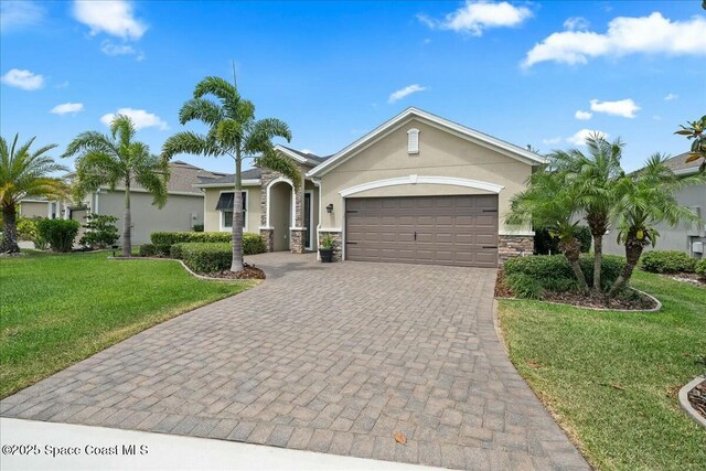 single story home with a front lawn, stucco siding, an attached garage, decorative driveway, and stone siding