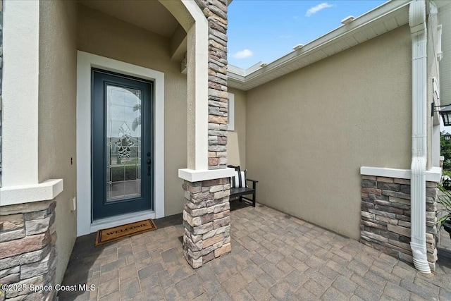 view of exterior entry featuring stucco siding and stone siding