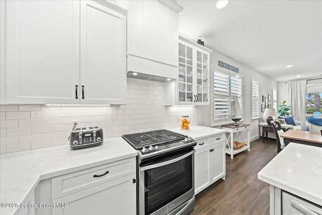kitchen featuring glass insert cabinets, dark wood-type flooring, light countertops, white cabinetry, and gas stove