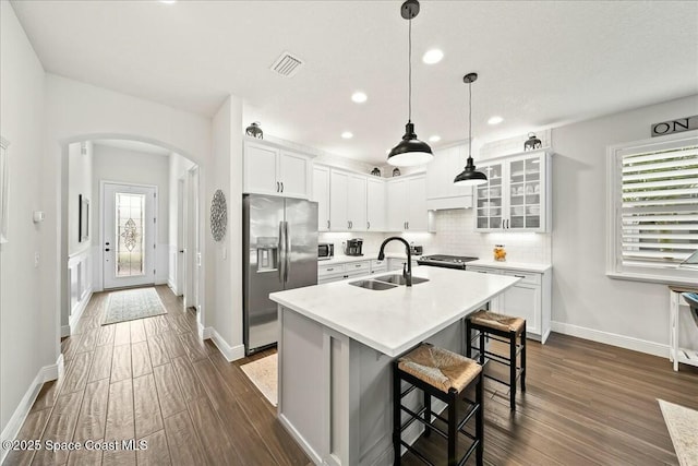 kitchen with stainless steel appliances, visible vents, a sink, arched walkways, and baseboards