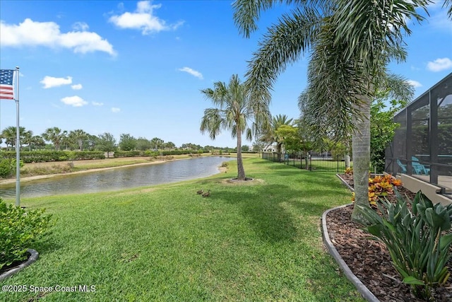 exterior space featuring fence, a lawn, and a water view
