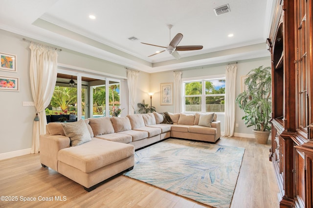 living room featuring a healthy amount of sunlight, a ceiling fan, and a raised ceiling