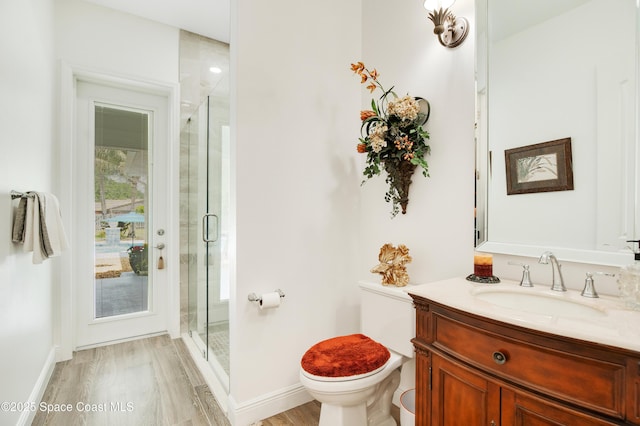 bathroom with a stall shower, toilet, baseboards, and wood finished floors