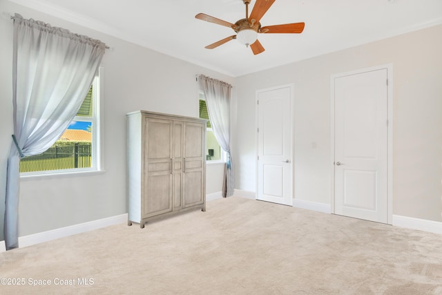 unfurnished bedroom featuring light colored carpet, baseboards, and ceiling fan