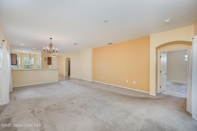 6921 Abbeyville Rd, Melbourne, FL 32940 - unfurnished living room with light colored carpet, visible vents, baseboards, an inviting chandelier, and arched walkways