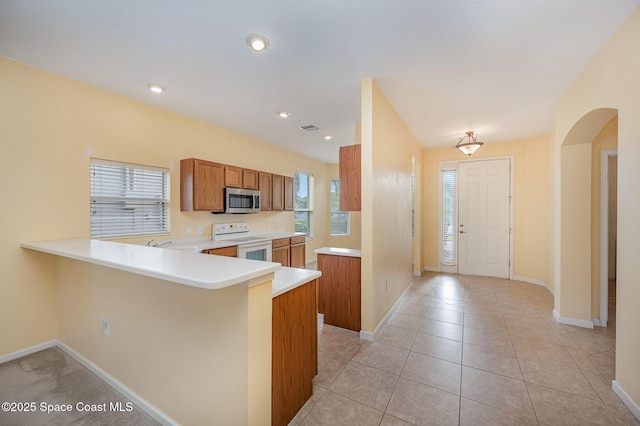 6921 Abbeyville Rd, Melbourne, FL 32940 - kitchen featuring stainless steel microwave, brown cabinets, white range with electric stovetop, light countertops, and baseboards