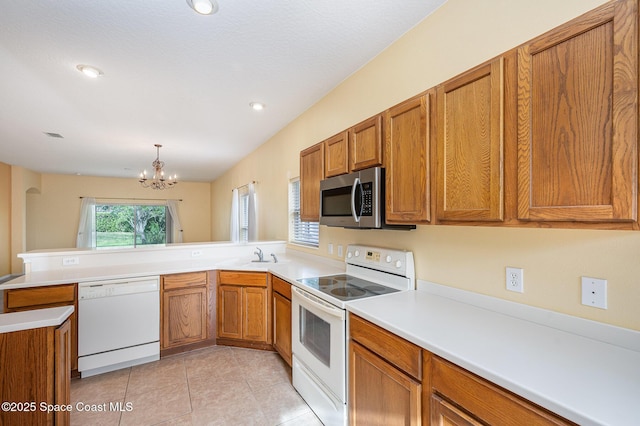 6921 Abbeyville Rd, Melbourne, FL 32940 - kitchen featuring white appliances, a chandelier, brown cabinetry, light tile patterned floors, and a peninsula