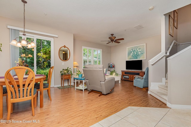 3321 San Jacinto Cir, Sanford, FL 32771 - living room featuring baseboards, ceiling fan with notable chandelier, stairway, and light wood-style floors