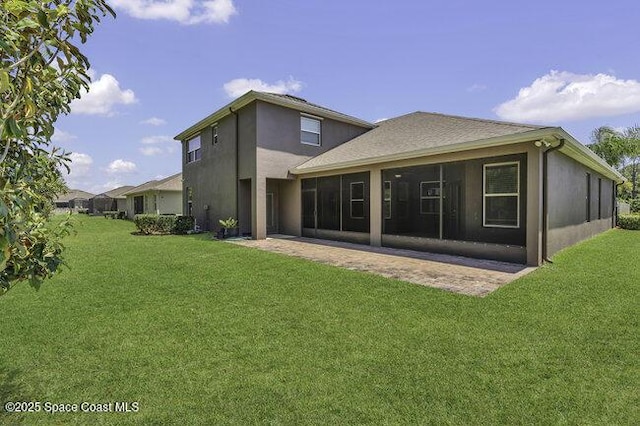 rear view of house with a lawn, stucco siding, and a sunroom