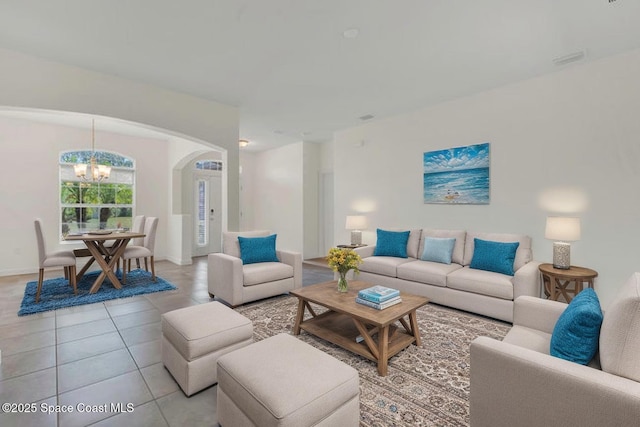 living room featuring baseboards, arched walkways, light tile patterned flooring, and a notable chandelier