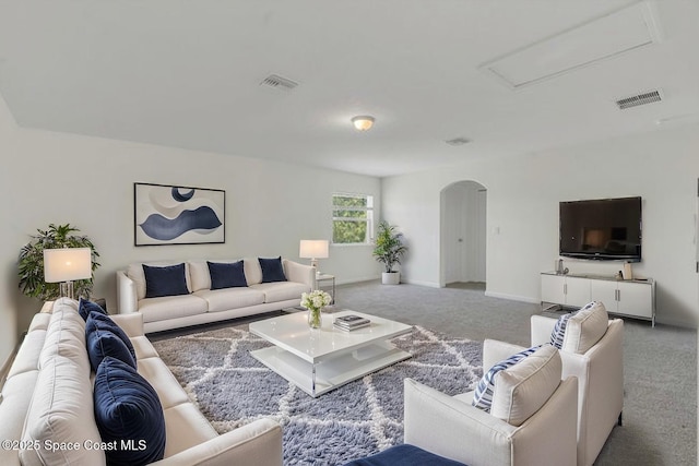 carpeted living area with arched walkways, baseboards, and visible vents