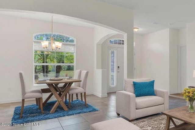 dining area featuring baseboards, arched walkways, and a notable chandelier