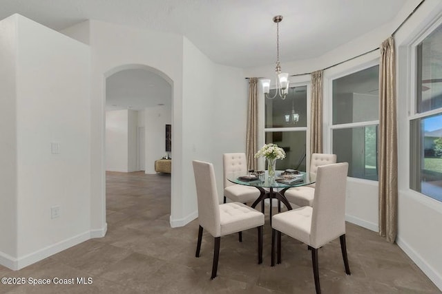 dining area with an inviting chandelier, arched walkways, and baseboards