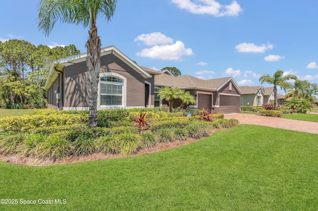 view of front of house featuring an attached garage, stucco siding, decorative driveway, and a front yard