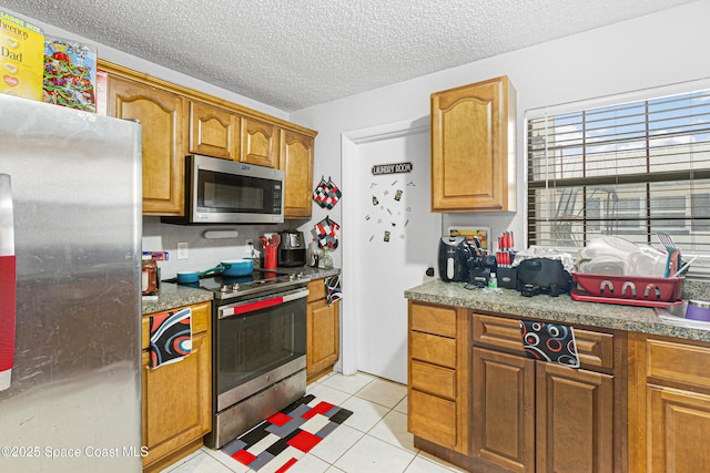 kitchen with brown cabinets, stainless steel appliances, a textured ceiling, and a sink
