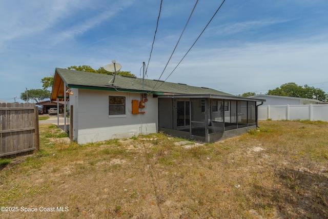 rear view of property with fence, a lawn, and a sunroom