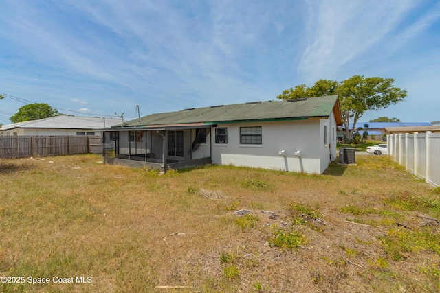 back of house with a lawn, a sunroom, fence, and central AC