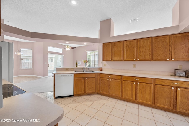 kitchen featuring brown cabinets, light countertops, a sink, and dishwasher