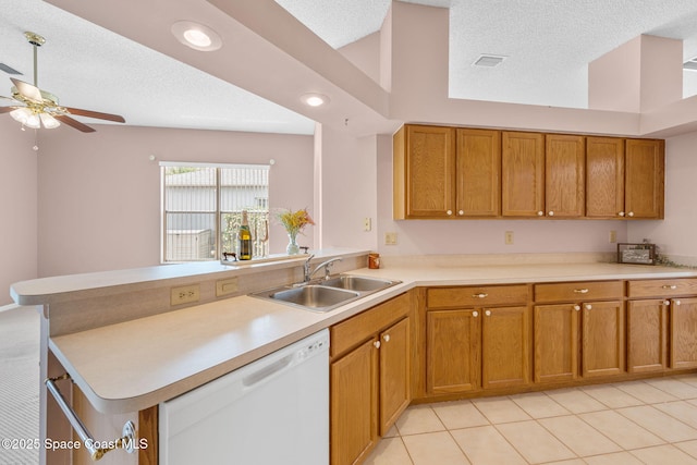kitchen featuring a ceiling fan, dishwasher, a sink, a peninsula, and brown cabinets