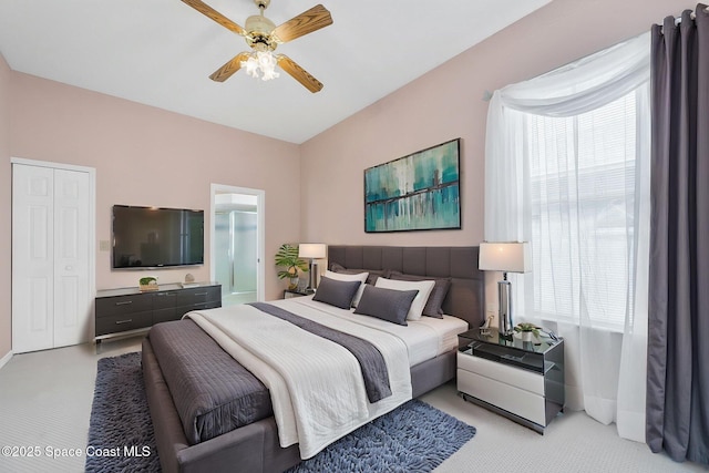 bedroom with light colored carpet, connected bathroom, baseboards, and a ceiling fan
