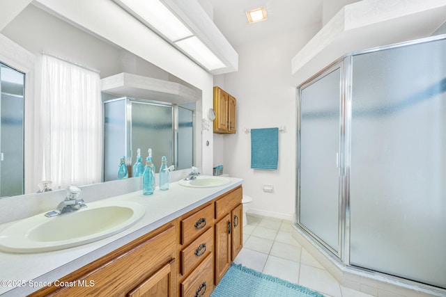 full bath with a stall shower, tile patterned flooring, double vanity, and a sink