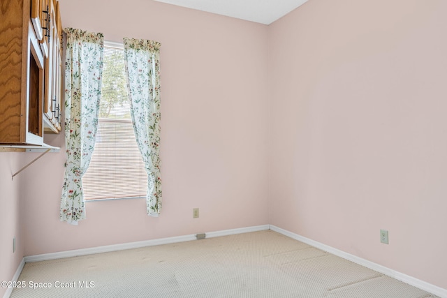 carpeted empty room featuring baseboards