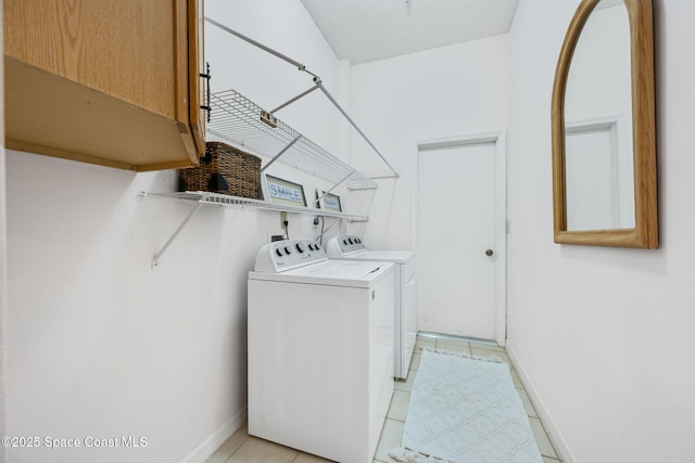 clothes washing area featuring washing machine and dryer, baseboards, and light tile patterned flooring