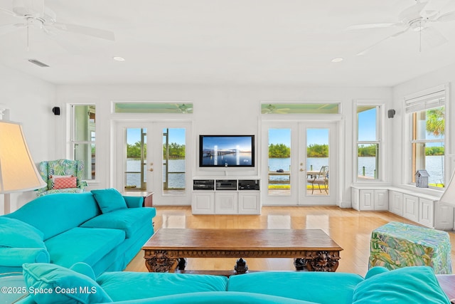 living area with french doors, a ceiling fan, and light wood-style floors