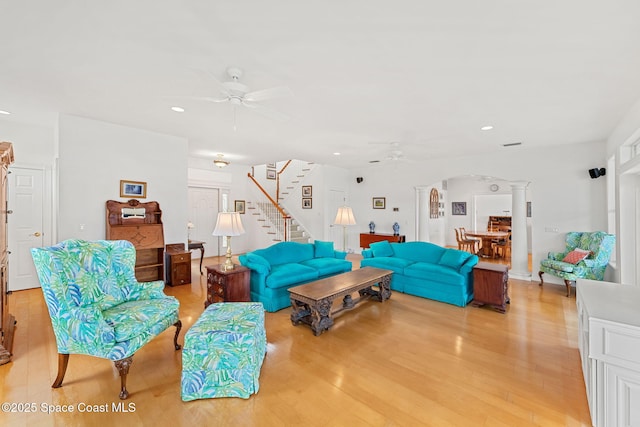 living room featuring a ceiling fan, stairs, ornate columns, recessed lighting, and light wood-style flooring