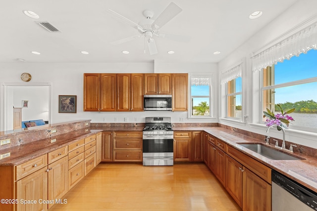 kitchen featuring visible vents, appliances with stainless steel finishes, a sink, a peninsula, and stone counters