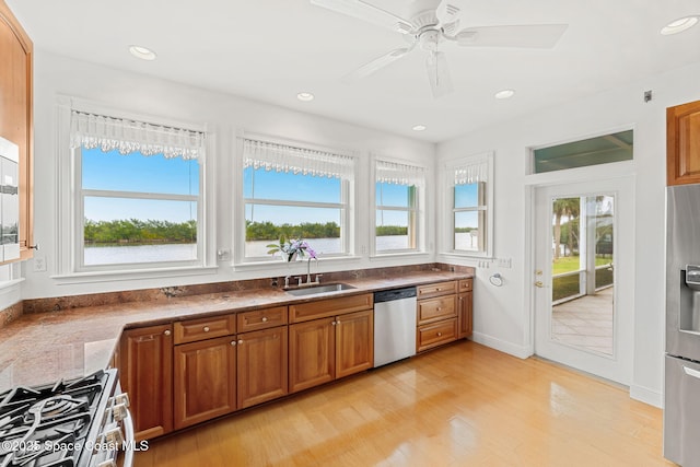 kitchen featuring stainless steel appliances, brown cabinetry, a sink, and a healthy amount of sunlight