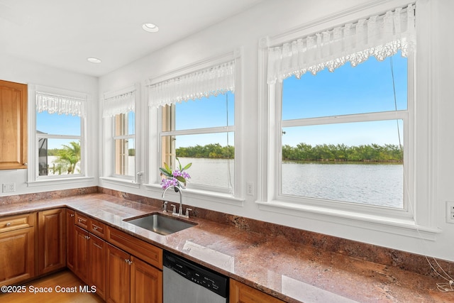 kitchen featuring a sink, dishwasher, a wealth of natural light, and brown cabinets
