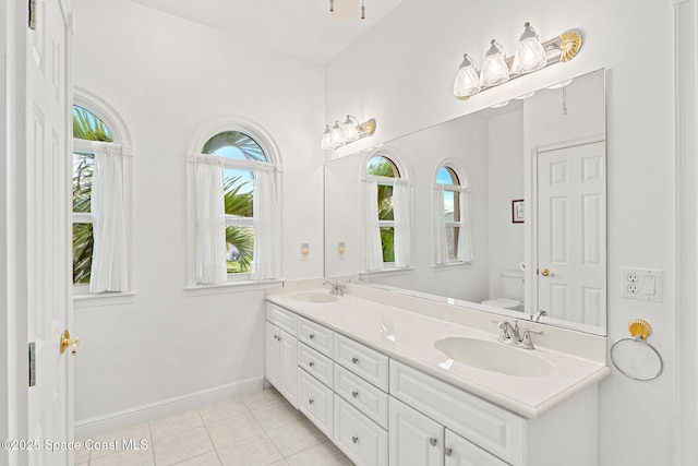 full bath with tile patterned flooring, a sink, baseboards, and double vanity