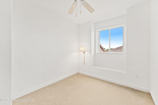 unfurnished room featuring light colored carpet, a ceiling fan, and baseboards