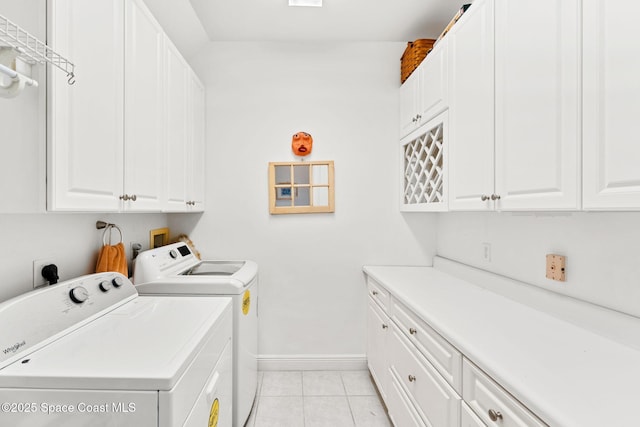 laundry area with separate washer and dryer, cabinet space, baseboards, and light tile patterned flooring