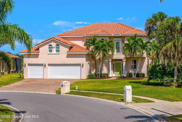 mediterranean / spanish-style house featuring a tile roof, a garage, stucco siding, a front yard, and driveway