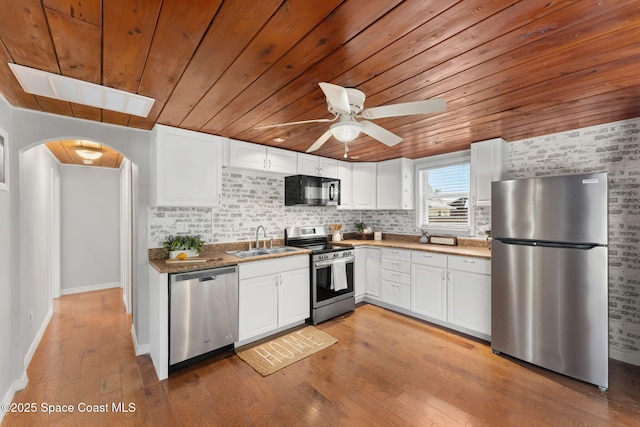 kitchen with a sink, appliances with stainless steel finishes, wood ceiling, and arched walkways