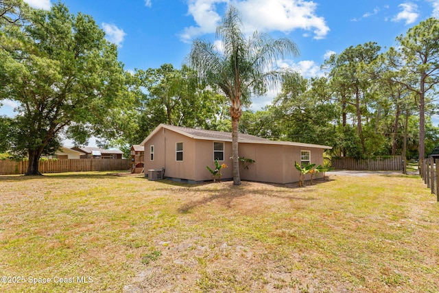 rear view of house with a lawn, a fenced backyard, and central air condition unit