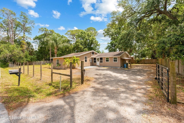 ranch-style house featuring a front lawn, fence, and driveway
