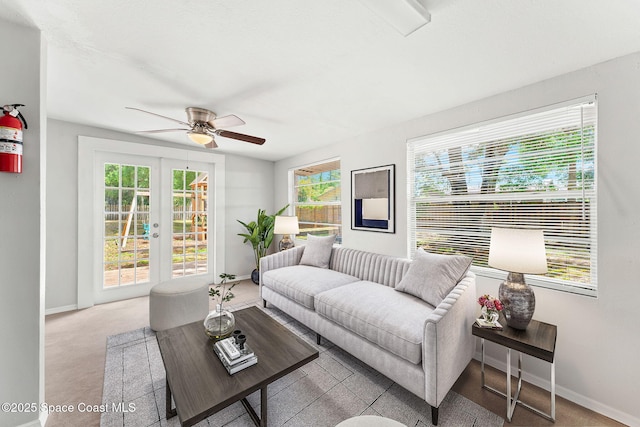 carpeted living room with a ceiling fan, baseboards, and french doors