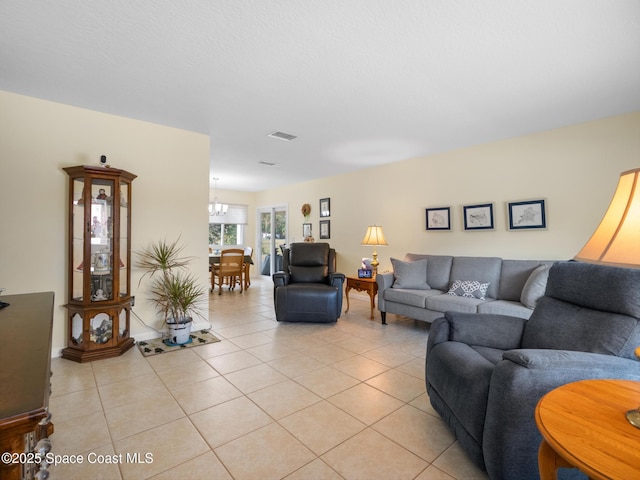 living room featuring an inviting chandelier, light tile patterned floors, and visible vents