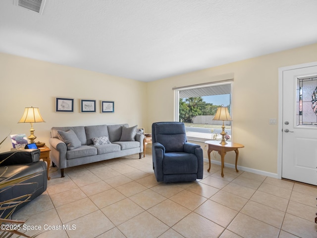 living room with light tile patterned floors, visible vents, and baseboards