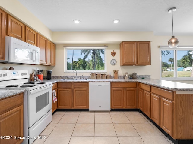 kitchen featuring brown cabinetry, white appliances, a peninsula, and a sink